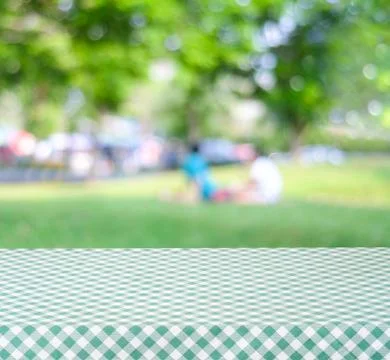 Empty table with green tablecloth over blur park with people and bokeh back.. Stock Photos