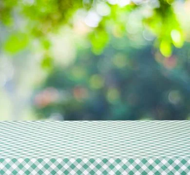 Empty table with green tablecloth over blur garden and bokeh background, fo.. Stock Photos
