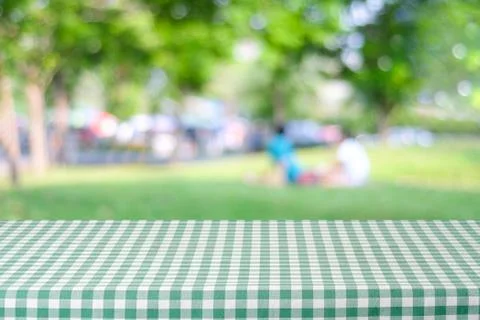 Empty table with green tablecloth over blur park with people and bokeh back.. Stock Photos