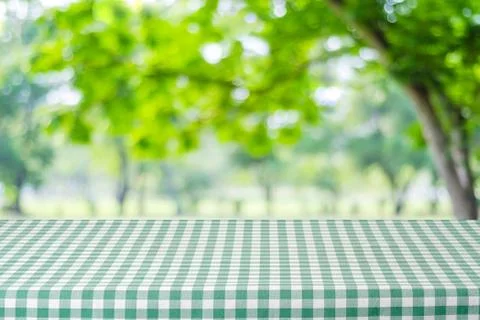 Empty table with green tablecloth over blur garden and bokeh background, fo.. Stock Photos