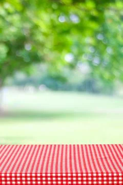Empty table with red and white tablecloth over blurred park nature background Fotos de archivo