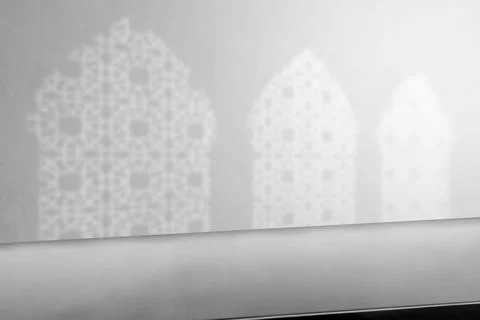 Empty table top with white shadow of three arched mosque windows on the wall Stock Photos