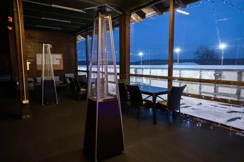 Empty tables and chairs inside a viewing room with a patio heater, overlooking Stock Photos