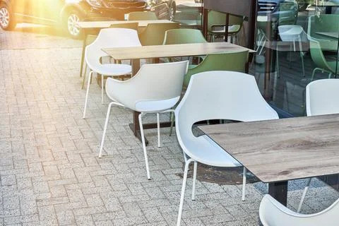 Empty tables on cafe terrace. White and green chairs outdoor. Sidewalk rest.. Stock Photos