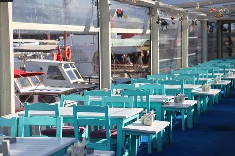 Empty tables in a port cafe in the background of boats at the pier, Turkey, N Stock Photos