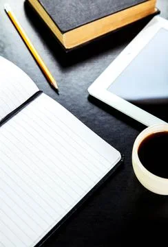 Empty tablet pc and a coffee and notebook with pen on the office desk Stock Photos