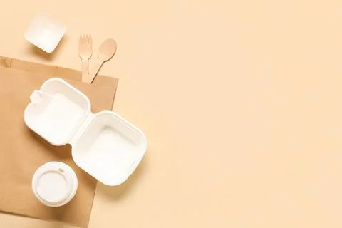 Empty takeaway food container, plastic bag, cup and wooden cutlery on beige b Stock Photos