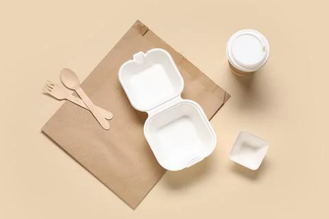 Empty takeaway food container, plastic bag, cup and wooden cutlery on beige b Stock Photos