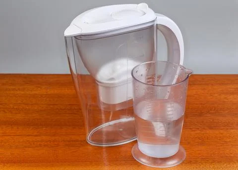 Empty tap water purifier jug and measuring cup with water Stock Photos