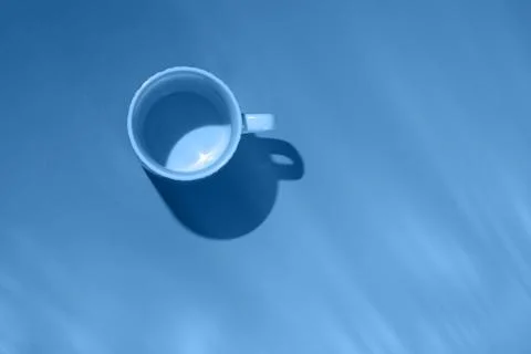 Empty tea cup on blue paper background. Coffee mug from above. Trendy color o Stock Photos
