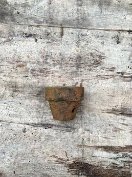 An empty terracotta clay pot, covered in moss, resting on an old wooden plank Stock Photos
