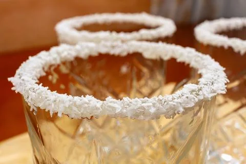 Empty textured glasses with white coconut flakes on the rims on a wooden board. Stock Photos
