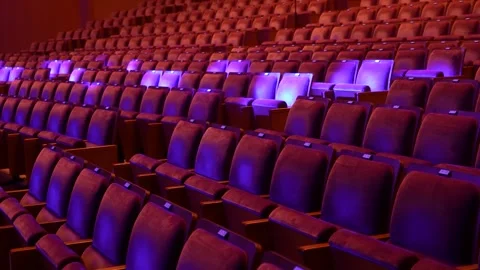 Empty theater seats illuminated by dramatic red and purple lighting Stock Footage 346343588