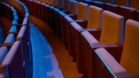 Empty theater seats in rows illuminated blue neon glow Video stock 322191032