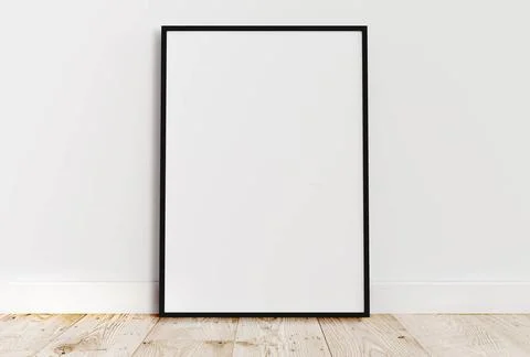 Empty thin black frame on light wooden floor with white wall behind it. Em... Stock-Fotos