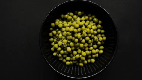 Empty tin can leaving frame revealing black bowl of green peas 4k Video stock 336646685