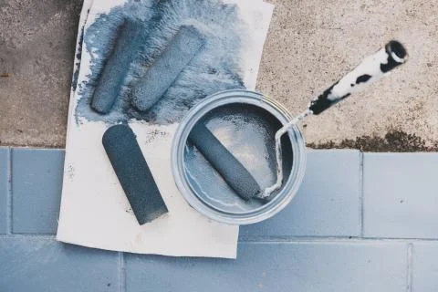 Empty tin of muted blue paint next to newly painted tfloor tiles Stock Photos