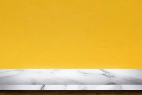 Empty top of white marble table with yellow concrete textured wall background Stock Photos