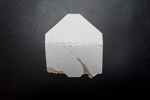 An empty, torn envelope lies on a dark surface, highlighting its aged texture Stock Photos