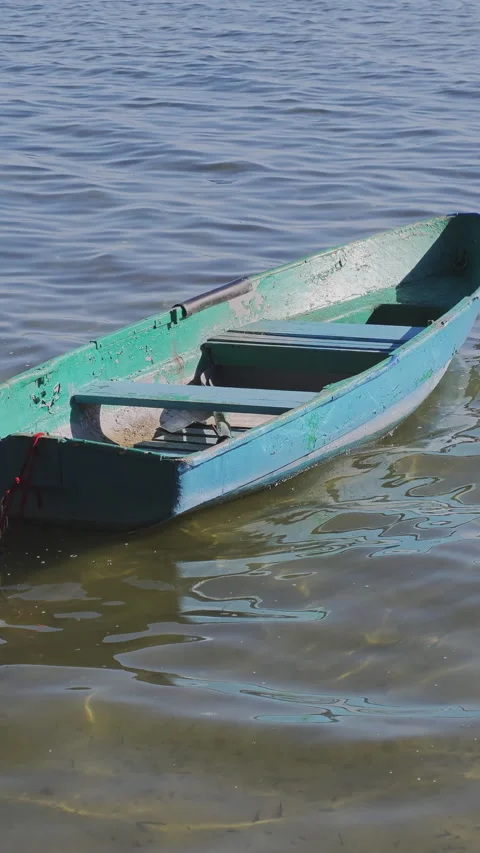 Empty traditional rowboat peacefully floating on the rippling surface Stockbeeldmateriaal 347457543