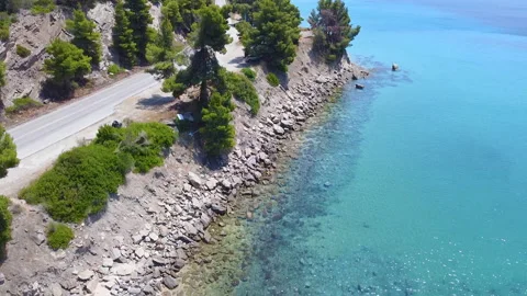 Empty traffic road on rocky coast by the blue transparent sea. Aerial view Stock Footage 135312435