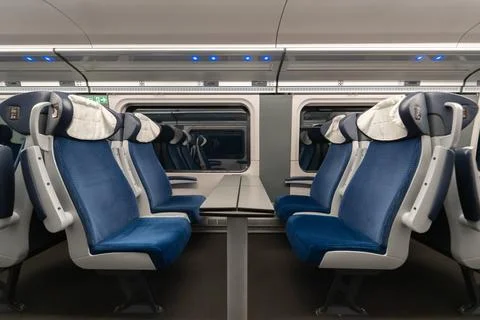 Empty train carriage interior with blue passenger seats and table by window Stock Photos