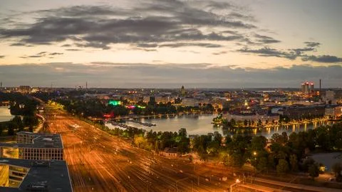 Empty train tracks glow amid city lights with dawn light in sky Stock Photos