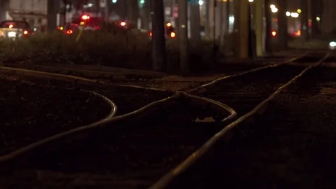 Empty train tracks at night with traffic behind in the background Video stock 73819329