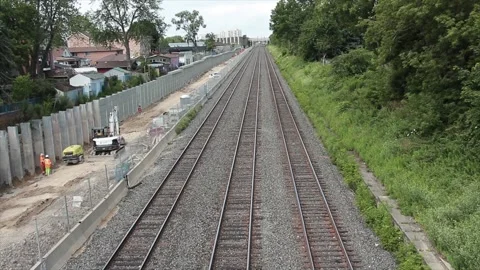 Empty train tracks with train passing with construction equipment to left Stock Footage 247753681