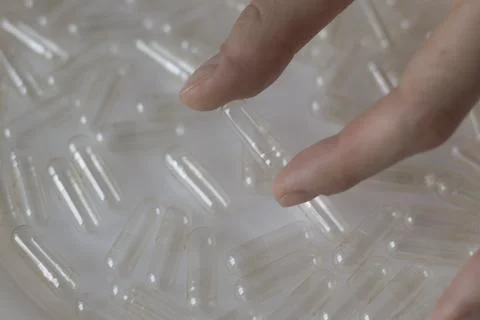 Empty Transparent Capsules in Hand on White Background. Stock Photos