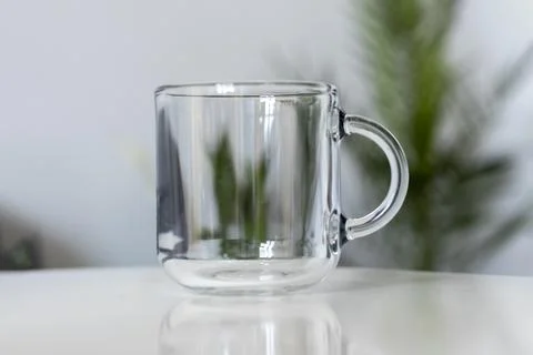 Empty transparent cup in close-up against the background of houseplants Stock Photos