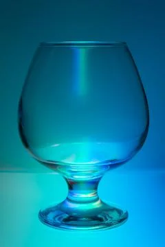 Empty transparent glass goblet in multicolored light Stock Photos