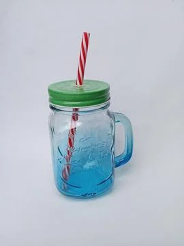 Empty transparent mason jar with a handle, red straw and green lid on white Stock Photos