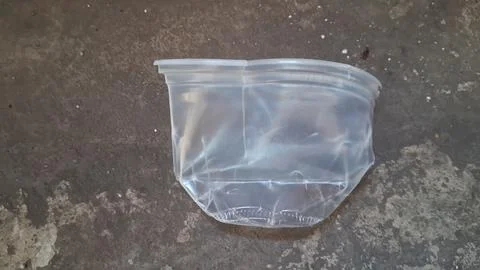 Empty transparent plastic container lying on a rustic grey ground Stock Photos