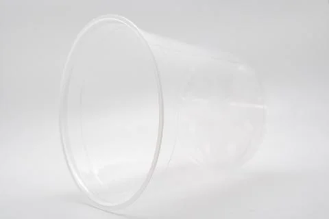 Empty transparent plastic cup lying on side isolated on white Stock Photos