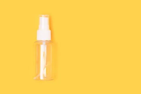 Empty transparent spray bottle on a yellow bright background. Stock Photos