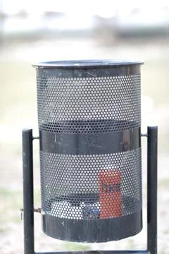 Empty trash can in the middle of a park on the street Stock Photos
