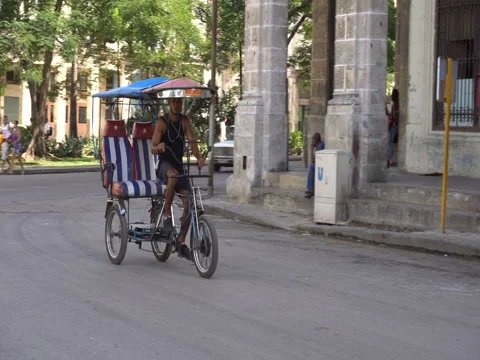Empty trishaw with cuban flag onto the seats is riding on street of Havan Stock-Footage 71057045