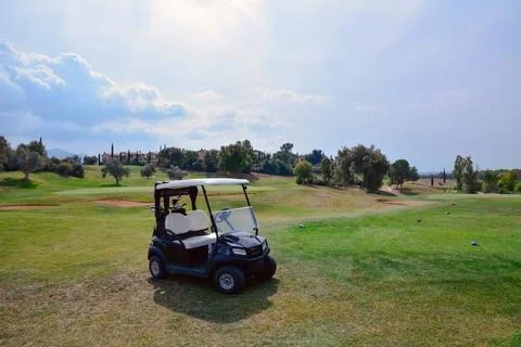 An empty two-seater golf cart stands on the lawn of a private golf club Stock Photos