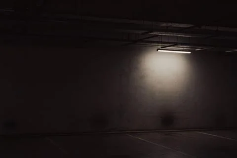 Empty underground garage. Empty parking lot with overhead dim light Stock Photos