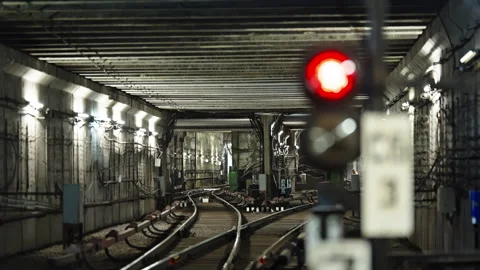 Empty underground metro tunnel with curving railway tracks and a glowing red Stock Footage 333051019