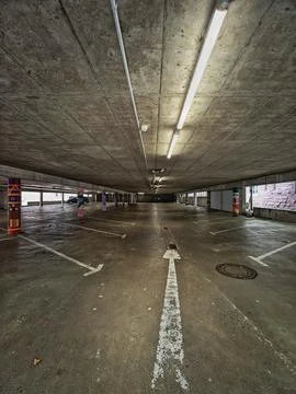Empty underground parking garage with concrete ceiling, fluorescent lights Stock Photos