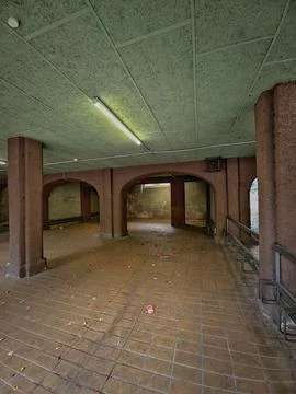 Empty underground passage with arched pillars, tiled floor, fluorescent light Stock Photos