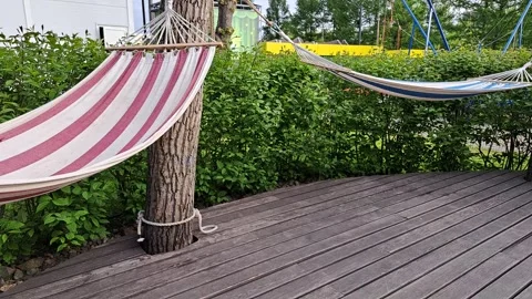 An empty, unoccupied hammock in a city park sways in the wind Stock Footage 309623428