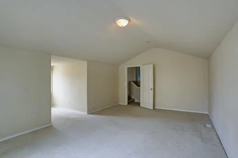 Empty upstairs room with vaulted ceiling, beige walls paint color and carpet  Stock Photos