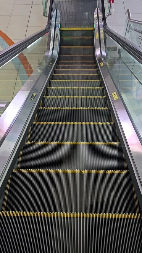 An empty, upward moving escalator with black steps and yellow safety lines Stock Footage 312003159