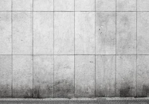 Empty urban interior with tiling on gray concrete wall and asphalt pavement Stock Photos