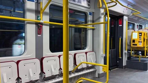 Empty urban train interior with yellow poles and red straps on a calm day, .. Stock Photos