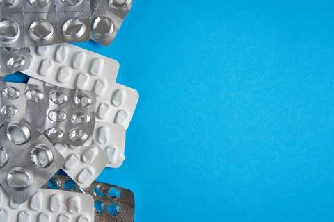 Empty used blisters from tablets silver and white color and pills lie on blue Stock Photos
