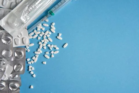 Empty used blisters from tablets silver and white color and pills lie on blue Foto stock